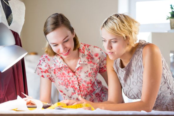Kaksi nuora naista opiskelevat ahkerasti pöydän ääressä.