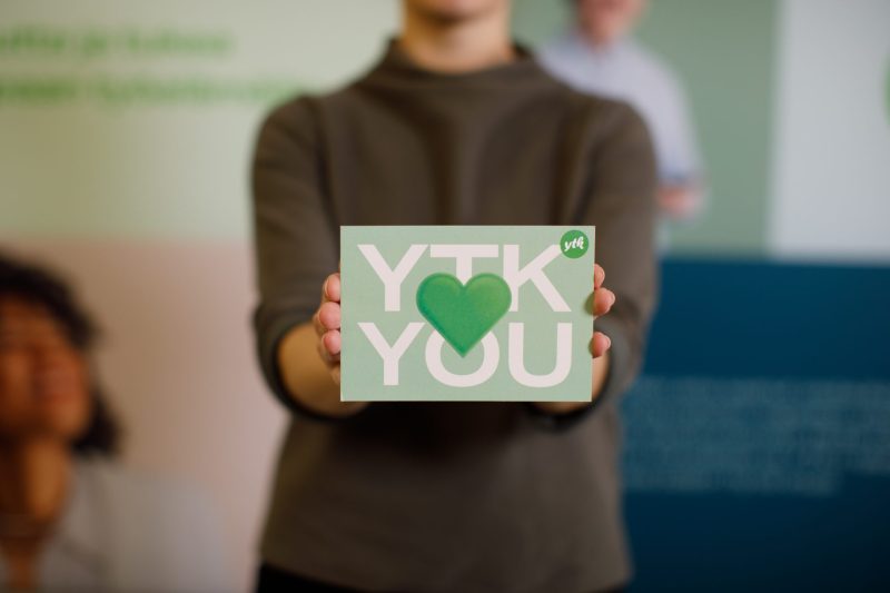 YTK:n työntekijä pitää käsissään kylttiä, jossa lukee "YTK Loves You"